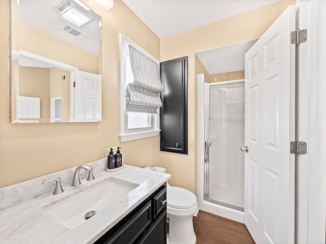 full bathroom featuring visible vents, toilet, a stall shower, vanity, and wood finished floors