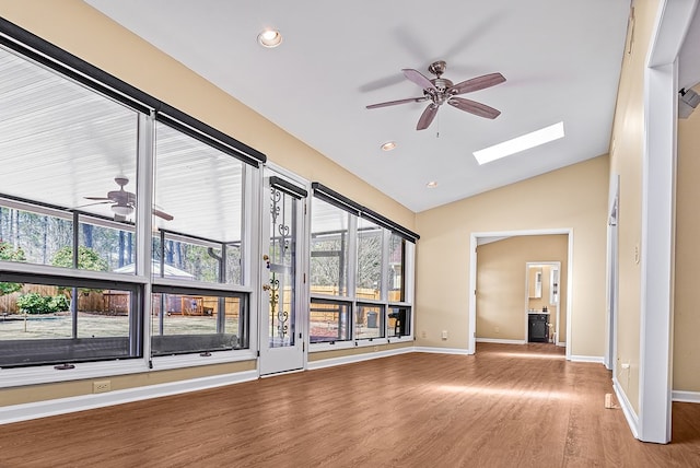 empty room with baseboards, a ceiling fan, lofted ceiling with skylight, wood finished floors, and recessed lighting