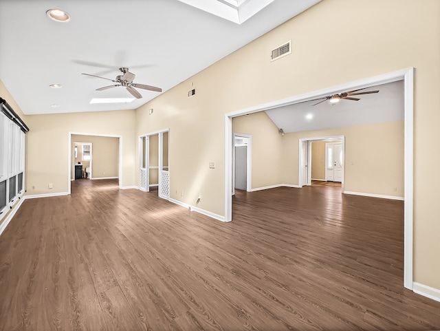 unfurnished living room with lofted ceiling with skylight, dark wood-style floors, visible vents, and a ceiling fan