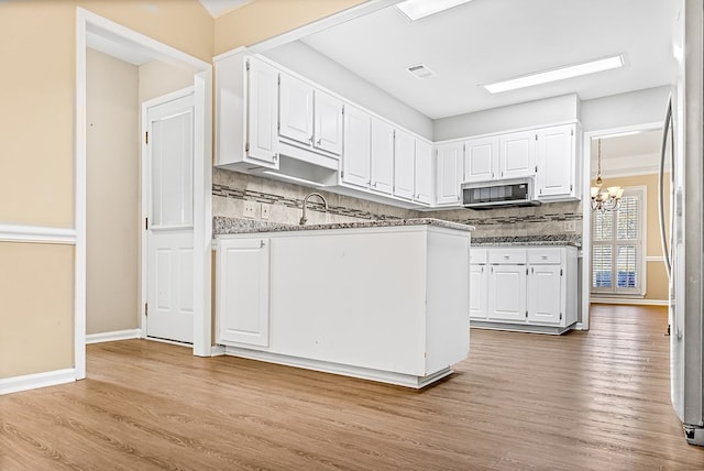 kitchen with appliances with stainless steel finishes, wood finished floors, visible vents, and white cabinetry