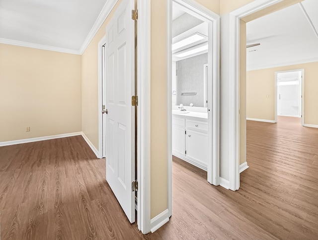 corridor with ornamental molding, baseboards, and wood finished floors