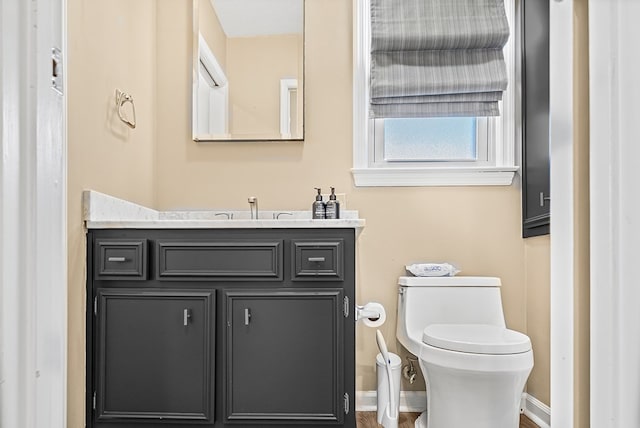 bathroom featuring baseboards, vanity, and toilet