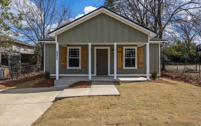 bungalow featuring board and batten siding, a front yard, a porch, and fence