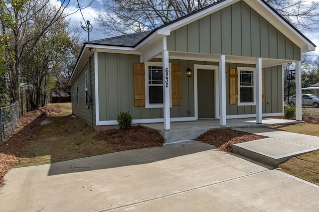 bungalow with board and batten siding, roof with shingles, a porch, and fence