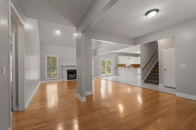 240 Lee Road 2099, Phenix City, AL 36870 - unfurnished living room featuring light wood-style floors, vaulted ceiling, baseboards, and plenty of natural light