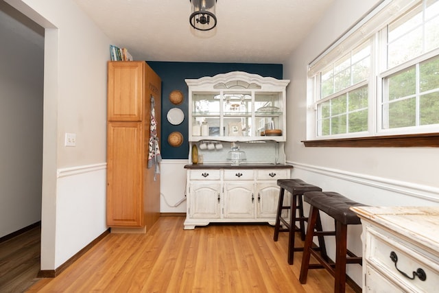 bar featuring light wood-type flooring and backsplash