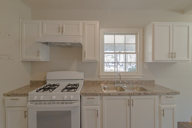 kitchen featuring under cabinet range hood, white range with gas stovetop, light countertops, and a sink