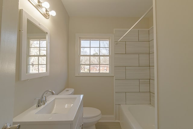 bathroom featuring toilet, bathing tub / shower combination, baseboards, and vanity