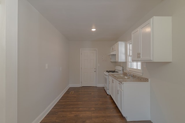 kitchen with gas range gas stove, light countertops, dark wood-type flooring, white cabinets, and a sink