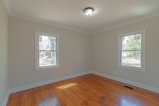 unfurnished room with a wealth of natural light, visible vents, baseboards, and wood finished floors