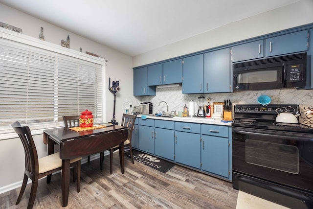 kitchen featuring blue cabinetry, sink, decorative backsplash, black appliances, and hardwood / wood-style flooring