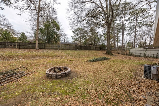 view of yard with central AC and a fire pit