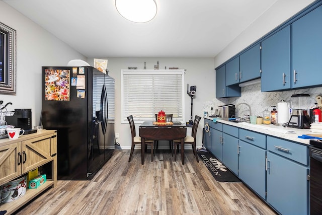 kitchen with decorative backsplash, dark hardwood / wood-style floors, blue cabinets, and black refrigerator with ice dispenser