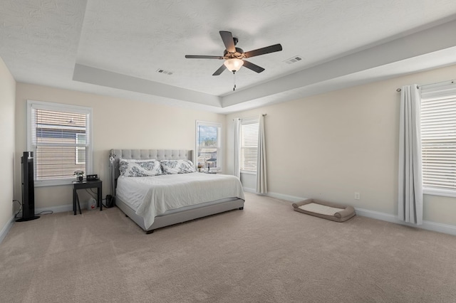 bedroom featuring carpet floors, a raised ceiling, visible vents, and baseboards