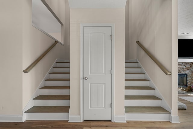 stairs featuring a textured ceiling, wood finished floors, and baseboards