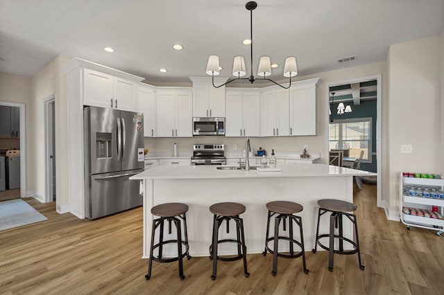 kitchen featuring visible vents, light countertops, appliances with stainless steel finishes, light wood finished floors, and an inviting chandelier