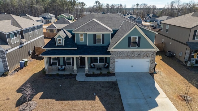 craftsman-style house featuring driveway, a residential view, an attached garage, covered porch, and central air condition unit