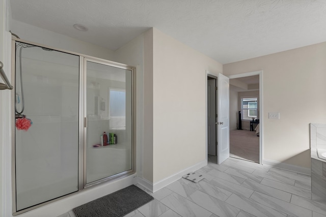 bathroom with a textured ceiling, a stall shower, a bathing tub, and baseboards