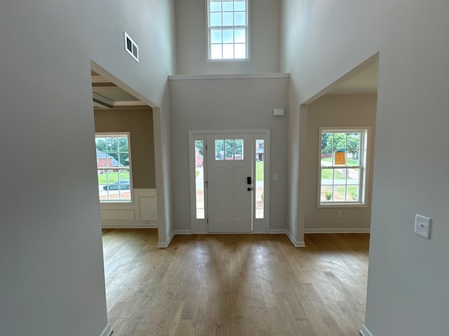 foyer entrance with plenty of natural light, light hardwood / wood-style floors, and a towering ceiling