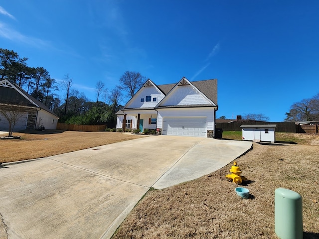 view of front facade with driveway, stone siding, an attached garage, a storage unit, and a front lawn