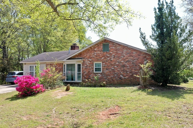 view of front of home with a chimney, a front yard, and brick siding