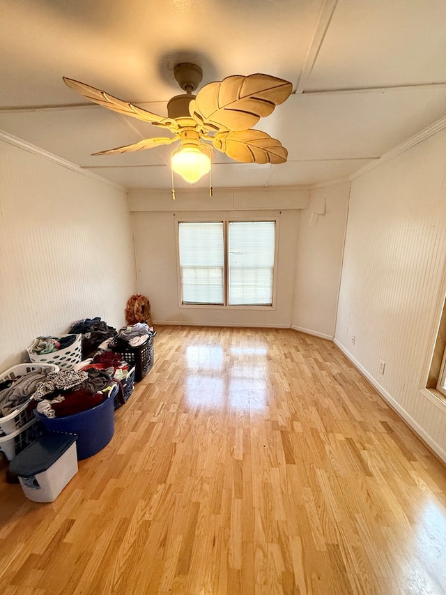empty room with light wood finished floors, crown molding, baseboards, and a ceiling fan