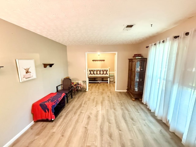 sitting room with a textured ceiling, baseboards, and wood finished floors