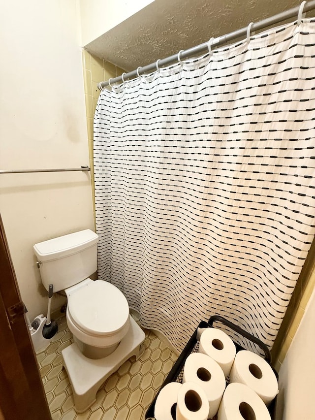 full bathroom with toilet, a shower with shower curtain, and a textured ceiling