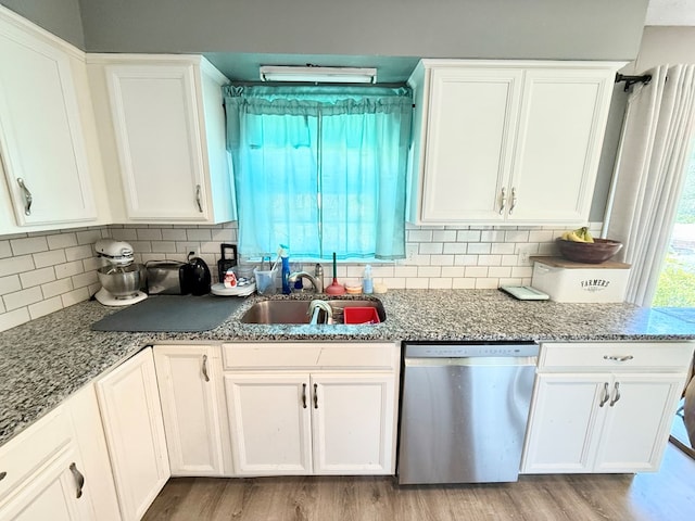 kitchen with light wood-style floors, a sink, stainless steel dishwasher, and white cabinets