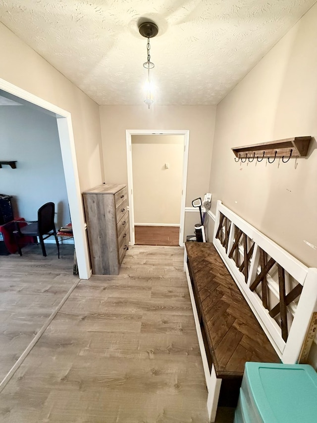 corridor featuring light wood-style floors and a textured ceiling