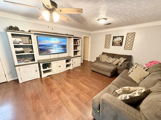 living room with crown molding, visible vents, wood finished floors, and ceiling fan