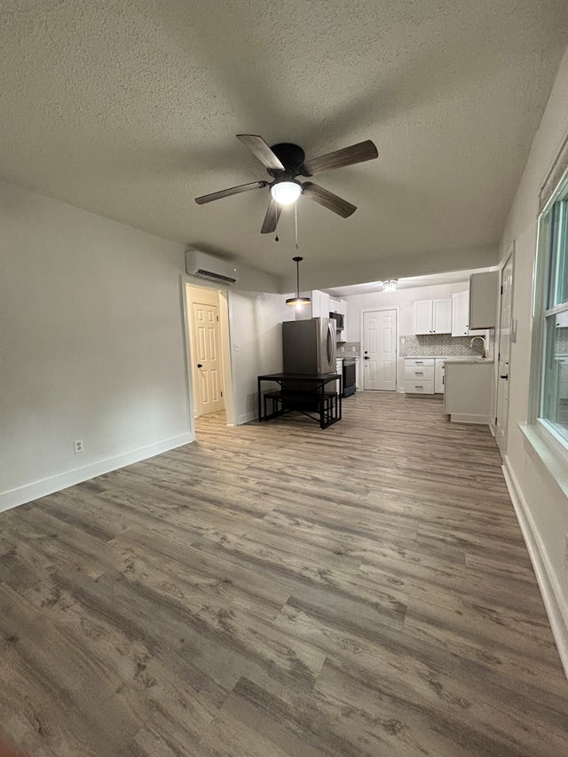 4026 Bowman St, Columbus, GA 31903 - unfurnished living room with a wall mounted AC, a textured ceiling, ceiling fan, and dark wood-style flooring