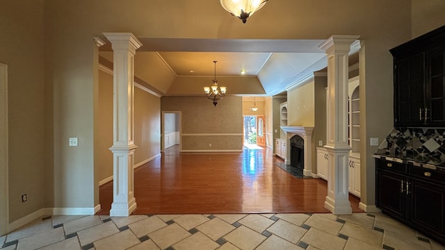 kitchen featuring ornamental molding, a notable chandelier, a premium fireplace, light hardwood / wood-style floors, and white cabinetry