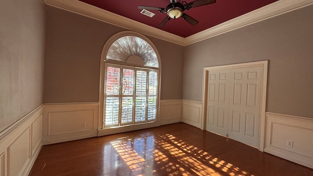 spare room featuring ceiling fan, dark wood-type flooring, and ornamental molding