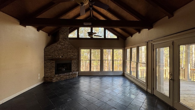 unfurnished sunroom featuring vaulted ceiling with beams, ceiling fan, a stone fireplace, and wooden ceiling