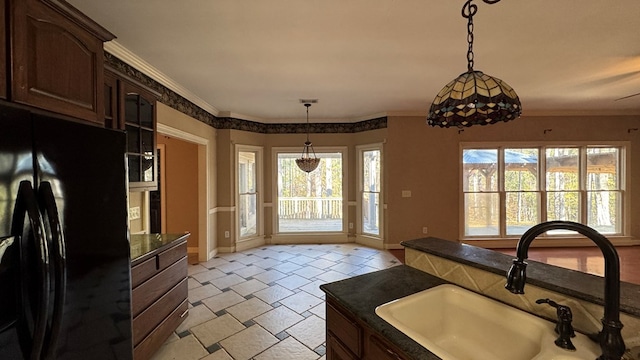 kitchen featuring black refrigerator, sink, hanging light fixtures, ornamental molding, and dark brown cabinetry