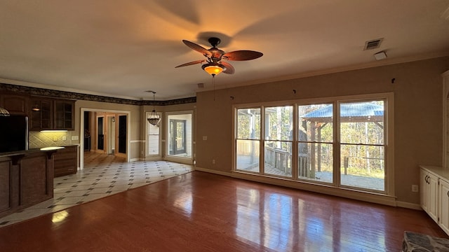 unfurnished living room with ceiling fan with notable chandelier, light hardwood / wood-style floors, and ornamental molding