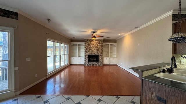 unfurnished living room with sink, built in features, plenty of natural light, and light wood-type flooring