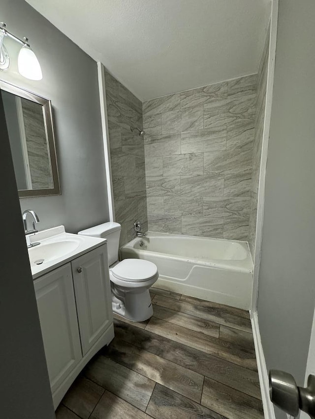 full bathroom featuring hardwood / wood-style floors, vanity, toilet, and tiled shower / bath