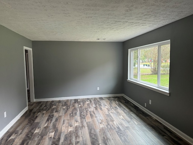 empty room with a textured ceiling and dark wood-type flooring