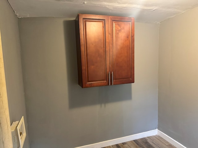 clothes washing area with cabinets and wood-type flooring