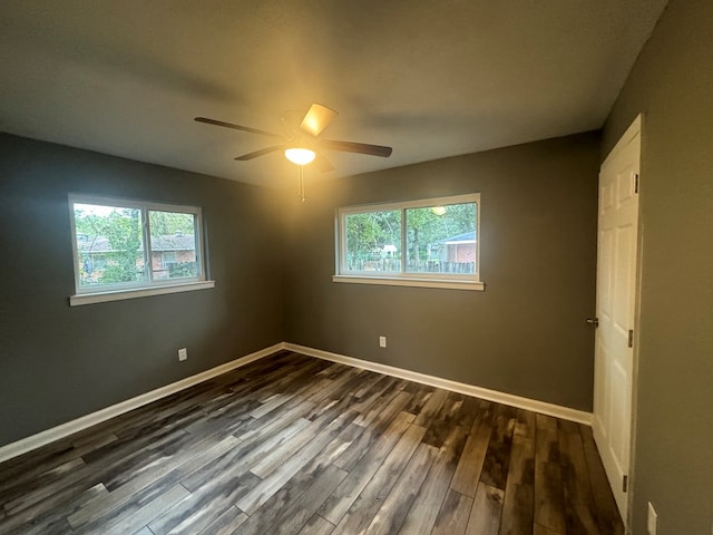 empty room with ceiling fan, a healthy amount of sunlight, and dark wood-type flooring