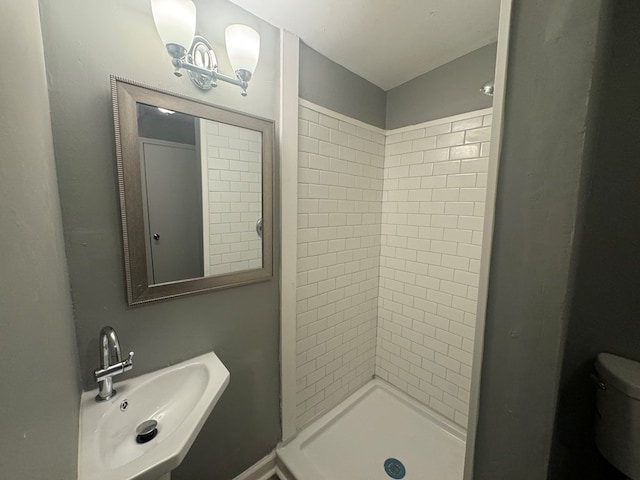 bathroom featuring toilet, sink, and tiled shower