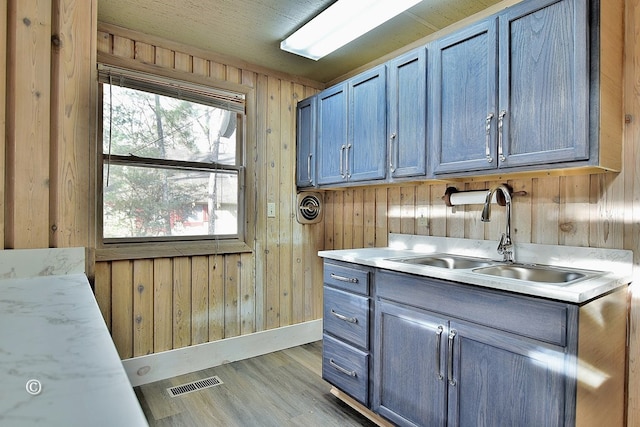 washroom featuring sink, light hardwood / wood-style floors, and wood walls