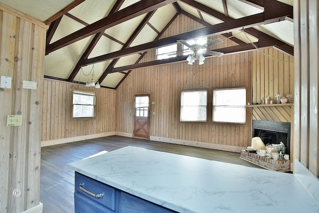 interior space featuring dark wood-type flooring, wood walls, a fireplace, and beamed ceiling