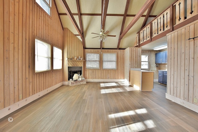 unfurnished living room with beamed ceiling, wood-type flooring, and wood walls