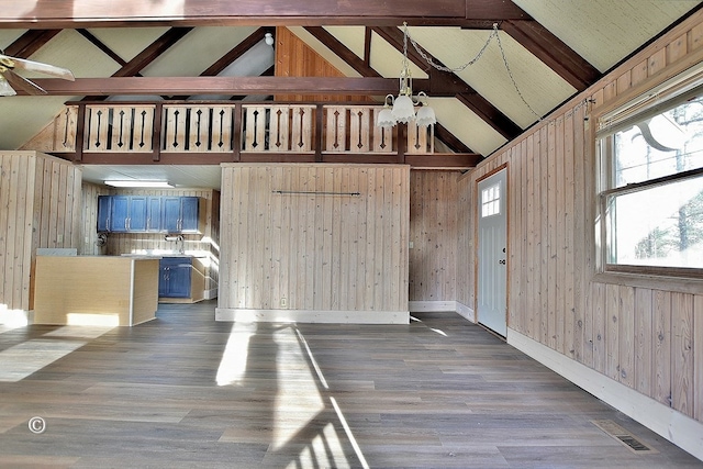 unfurnished living room with hardwood / wood-style flooring, wooden walls, high vaulted ceiling, and beam ceiling