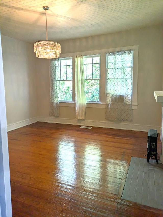 empty room featuring hardwood / wood-style floors, a wealth of natural light, and a chandelier