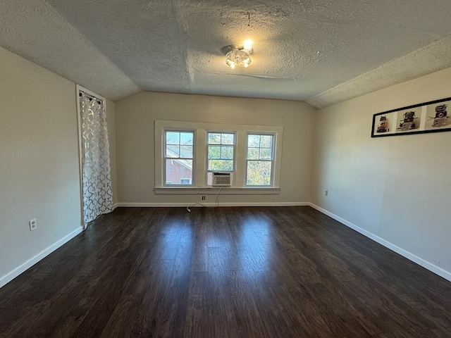 empty room with a textured ceiling, dark hardwood / wood-style flooring, cooling unit, and lofted ceiling