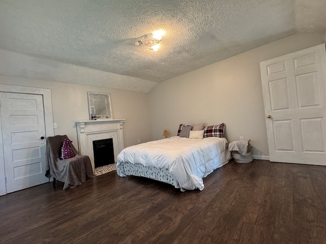 bedroom with dark hardwood / wood-style flooring, lofted ceiling, and a textured ceiling